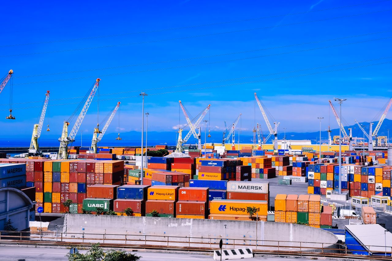 Mastering the First Impression: Your intriguing post title goes here A bustling shipping port with colorful stacked containers and numerous cranes under a clear blue sky.